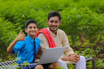 Education concept : Indian farmer's boy using laptop at agriculture field and showing thumps up.