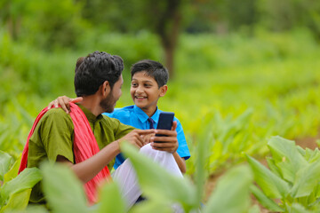 Wall Mural - Indian farmer using smartphone with his child at green turmeric agriculture field.