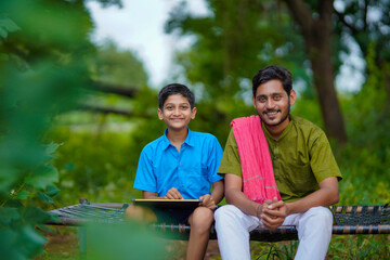 Wall Mural - Cute indian farmer child studying with his father at home