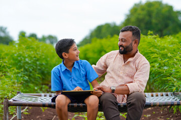 Wall Mural - Cute indian farmer child studying with his father at home