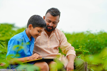 Wall Mural - Cute indian farmer child studying with his father at home