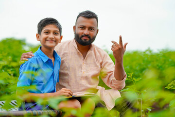 Wall Mural - Cute indian farmer child studying with his father at home