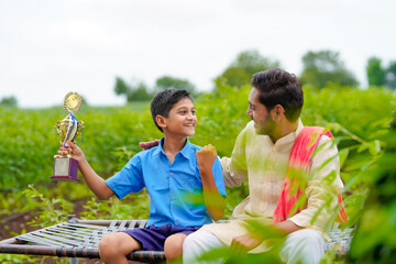 Wall Mural - clever school boy holding winning trophy and celebrate with his father.