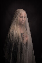 Blonde Girl With Veil In Dark Studio Portrait Like Holy Mary Or Bride
