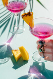 Fototapeta Uliczki - A women hand with jewelry holding a cocktail glasses with campari decorated with pineapple pieces.