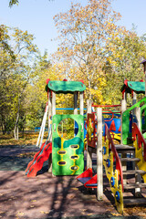 Sticker - colorful wooden rides, slides and houses on children's playground in public city park on sunny autumn day