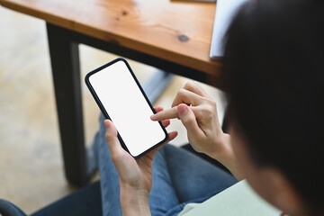 Poster - Top view of short hair man using a white blank screen smartphone in the comfortable living room.