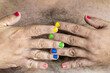 Close-up with selective focus to a male hand with colorfully painted fingernails on the hairy chest.