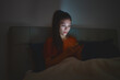 Woman sleeping using phone in bed staying up late at night reducing her sleep time which is bad for mental health and depression.