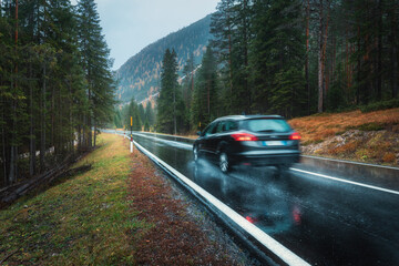 Wall Mural - blurred car in motion on the road in autumn forest in rain. perfect asphalt mountain road in overcas