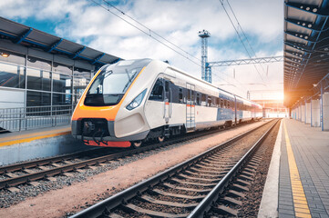 High speed train on the railway station at sunset