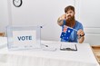 © Krakenimages.com - Caucasian man with long beard at political campaign election holding australia flag pointing with finger to the camera and to you, confident gesture looking serious