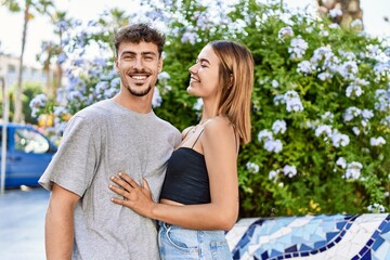 Young hispanic couple smiling happy and hugging standing at the city.