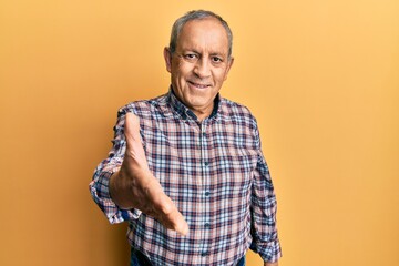 Poster - Handsome senior man with grey hair wearing casual shirt smiling friendly offering handshake as greeting and welcoming. successful business.