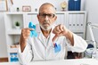 © Krakenimages.com - Mature doctor man holding blue ribbon at the clinic with angry face, negative sign showing dislike with thumbs down, rejection concept