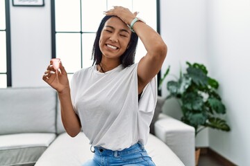 Sticker - Young hispanic woman holding menstrual cup stressed and frustrated with hand on head, surprised and angry face