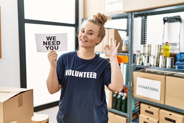 Sticker - Young caucasian woman volunteer holding we need you banner doing ok sign with fingers, smiling friendly gesturing excellent symbol