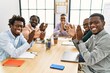 Group of african american business workers smiling and clapping looking to the camera at the office.