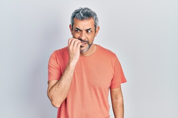 Sticker - Handsome middle age man with grey hair wearing casual t shirt looking stressed and nervous with hands on mouth biting nails. anxiety problem.