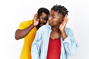 Poster - Young african american couple wearing casual clothes smiling with hand over ear listening an hearing to rumor or gossip. deafness concept.