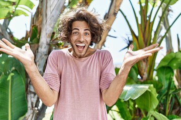 Sticker - Young hispanic man outdoors on a sunny day celebrating victory with happy smile and winner expression with raised hands