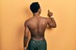 © Krakenimages.com - Young african american man wearing swimwear and swimmer glasses posing backwards pointing ahead with finger hand