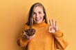 © Krakenimages.com - Young blonde woman holding bowl of star anise doing ok sign with fingers, smiling friendly gesturing excellent symbol