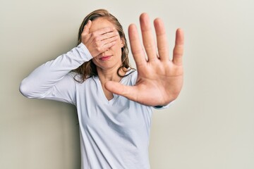 Sticker - Young blonde woman wearing casual clothes covering eyes with hands and doing stop gesture with sad and fear expression. embarrassed and negative concept.