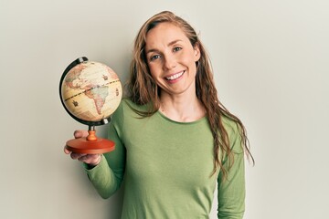 Poster - Young blonde woman holding vintage world ball looking positive and happy standing and smiling with a confident smile showing teeth