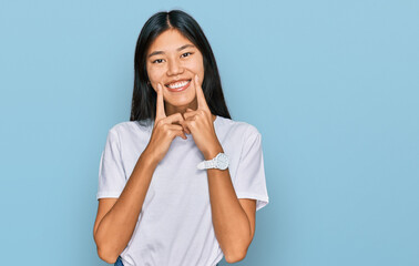 Wall Mural - Beautiful young asian woman wearing casual white t shirt smiling with open mouth, fingers pointing and forcing cheerful smile