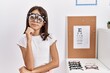 Young hispanic girl wearing optometry glasses serious face thinking about question with hand on chin, thoughtful about confusing idea