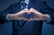 Handsome man show heart symbol, love icon for Business lover, I love my job, take care service concept. Smart Businessman wear blue suit shirt and tie making heart shape by his hand on blue background