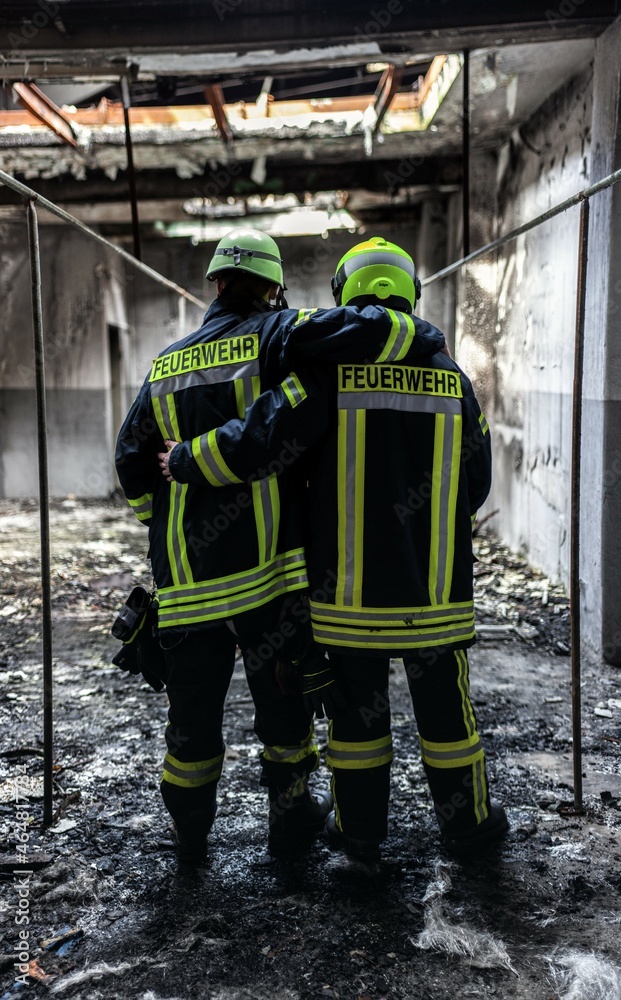 two firefighters embracing each other in the aftermath of a building ...