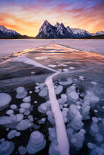 Stunning Sunrise With Leading Ice Creacked Line And Trapped Frozen Methane Bubbles Within Ice Surface, Lake Abraham, Alberta. Winter Storm In Canada.