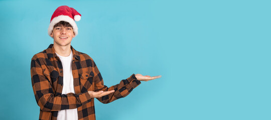 Wall Mural - young man with santa claus hat isolated on blue colored background