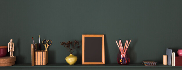 Desk at home office with supplies and shelf with frame, books and supplies. Minimalistic workspace.	