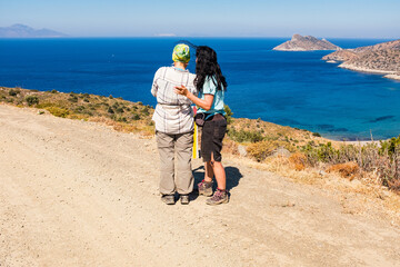 Two happy women look on the sea. Vacation free spirit travel mood.