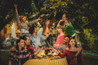 Multiracial friends enjoying dinner and drinking red wine in the garden - People having fun after dinner in the courtyard of the restaurant, girls dancing and people toasting - Friendship concept .