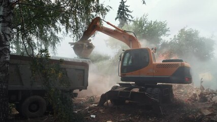 Wall Mural - Demolition of building, excavator at work, bucket loads debris and rubble with lot of dust into truck for removal.