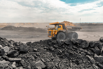 Wall Mural - Large quarry dump truck. Big yellow mining truck at work site. Loading coal into body truck. Production useful minerals. Mining truck mining machinery to transport coal from open-pit production