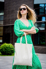 Canvas Print - Young beautyful woman with linen eco bag on city background.