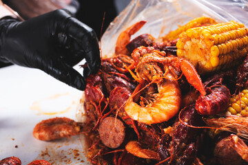 Wall Mural - A view of hand opening a plastic bag full of seafood boil, at a local restaurant.