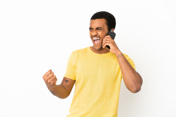 Wall Mural - African American handsome man using mobile phone over isolated white background celebrating a victory