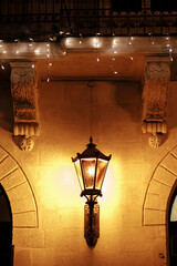 Wall Mural - Stylish christmas lantern and lights illumination on old building in evening. Atmospheric magic time. Christmas festive decor for winter holidays. Merry Christmas!