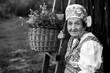 Portrait of an elderly woman in ethnic Eastern European clothing, outdoors. Black and white photo.