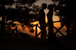 Beautiful, sweet lover couple body together, silhouette at sunset on top of a hill, next to trees, near to the sea.
