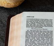 Open Holy Bible Book With Bread. Christian Biblical Concept Of God Jesus Christ - The Bread Of Life. The Teaching Of Spiritual Food From Heaven (manna). Sacrifice And Mercy Of Our Savior. A Close-up.