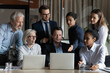 Effective teamwork. Older and younger men women multiracial business executives colleagues gather for brainstorm at workplace look on laptop screens of two diverse team leaders propose solutions ideas