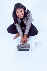 Wall Mural - Young happy female sitting on the floor in front of the laptop