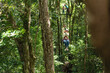 Mujer colgando y asustada en cables de canopy de la selva en costa rica